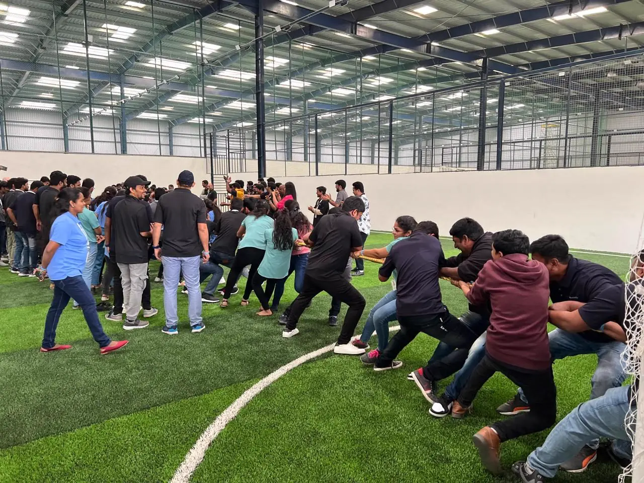Colleagues in a tug of war on the indoor turf