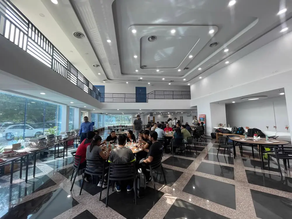 A double-height dining hall with a glass wall and a buffet line