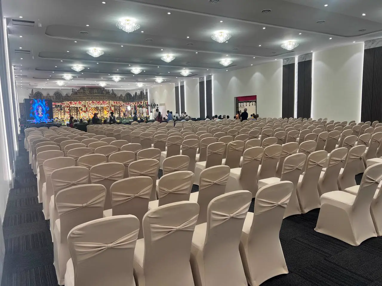 A hall set with rows of covered chairs facing a temple-style stage