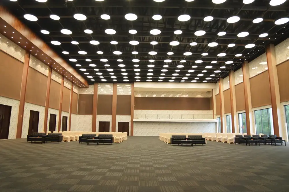 The pillarless grand hall under a grid of round ceiling lights, with a stage at the far end