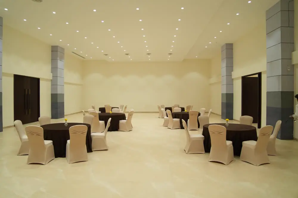 A smaller marble-floored hall with round tables and covered chairs