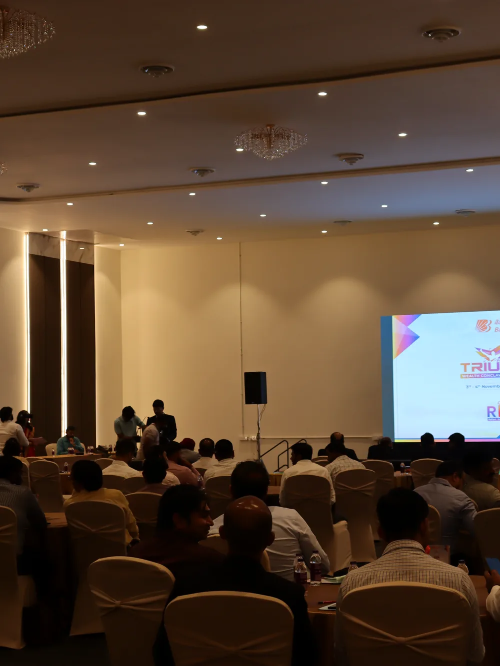 A full-house plenary facing an LED stage