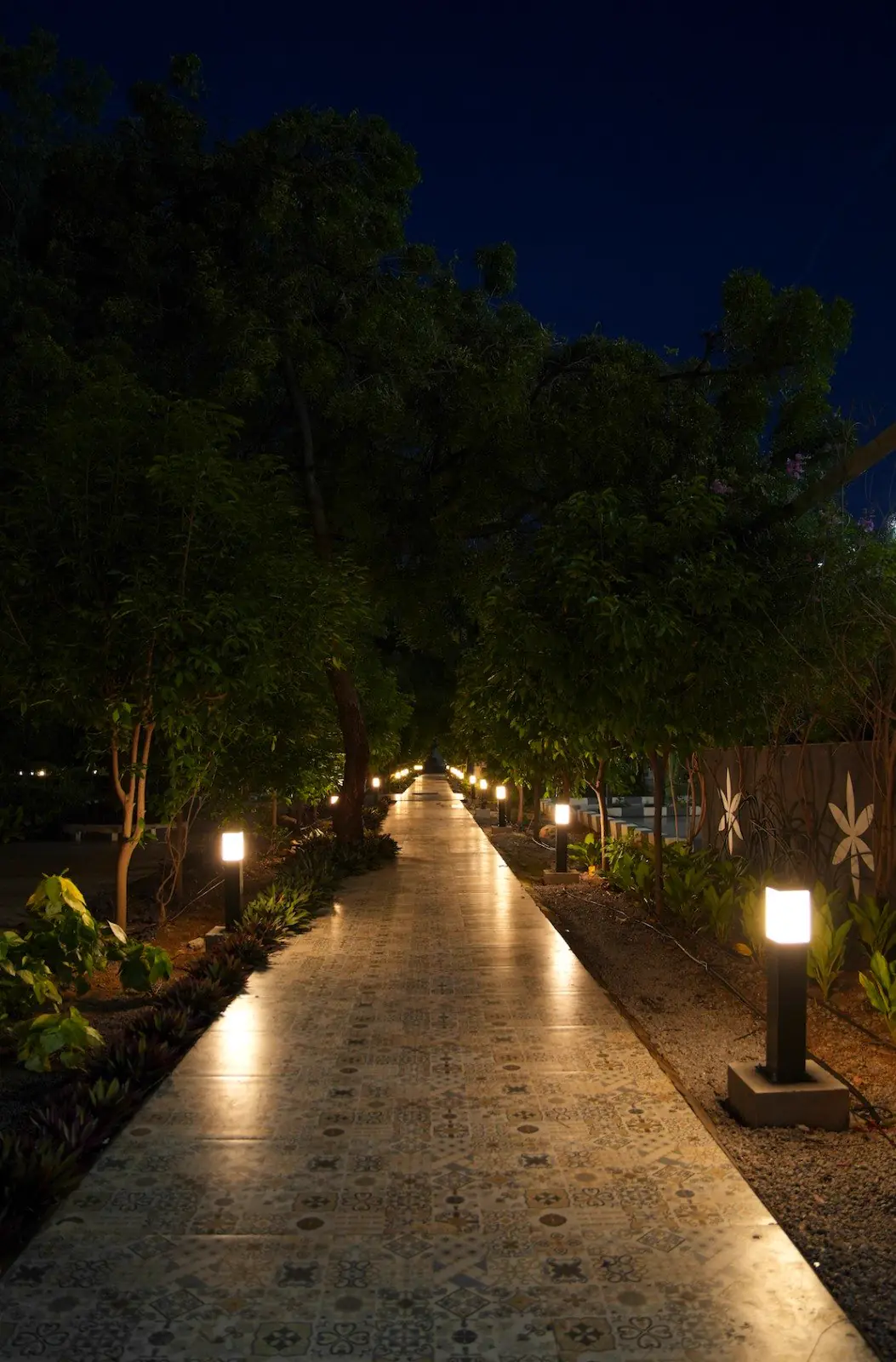 A tiled garden promenade lit by bollards at night