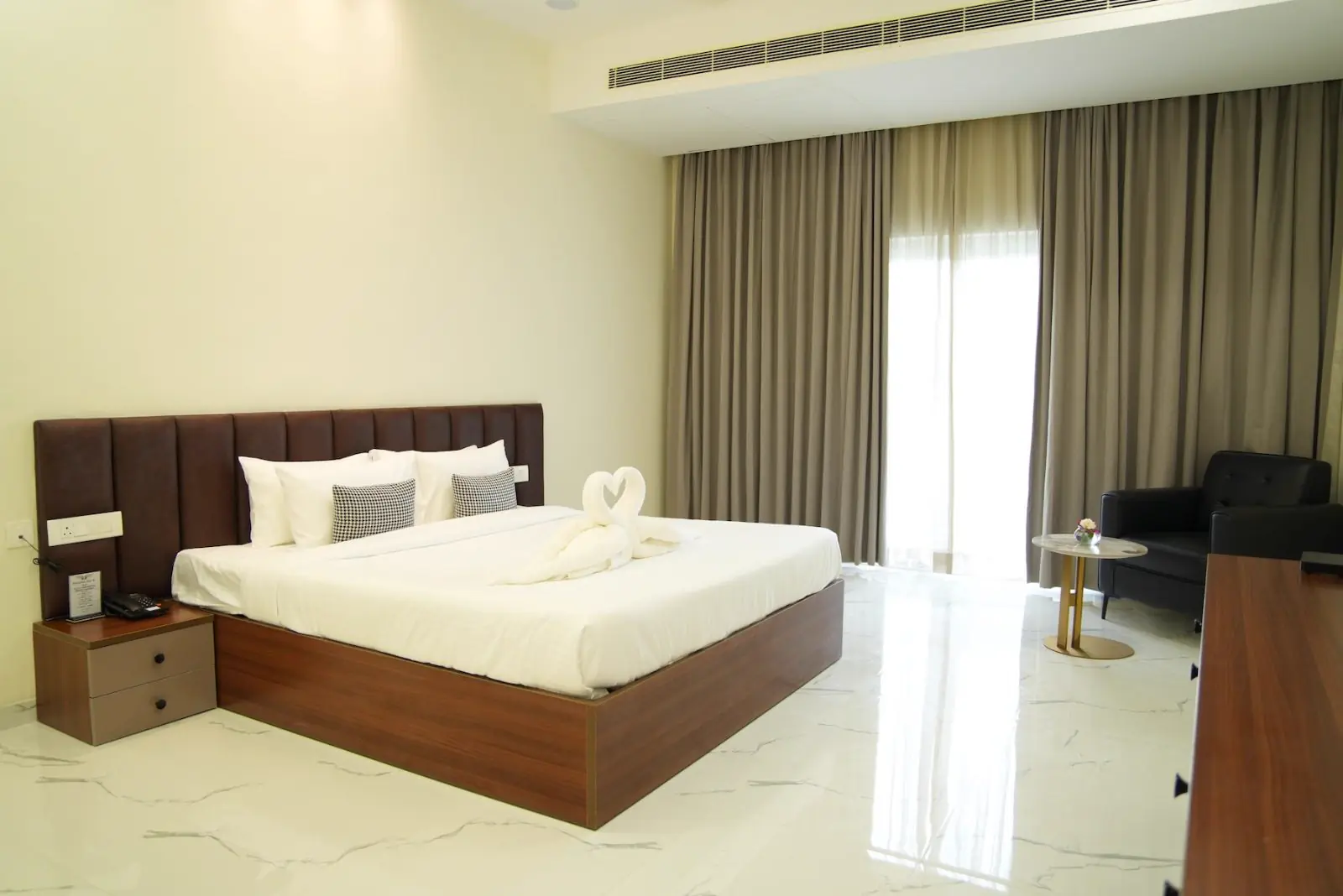 A guest room with a king bed, a sofa and a balcony over the gardens