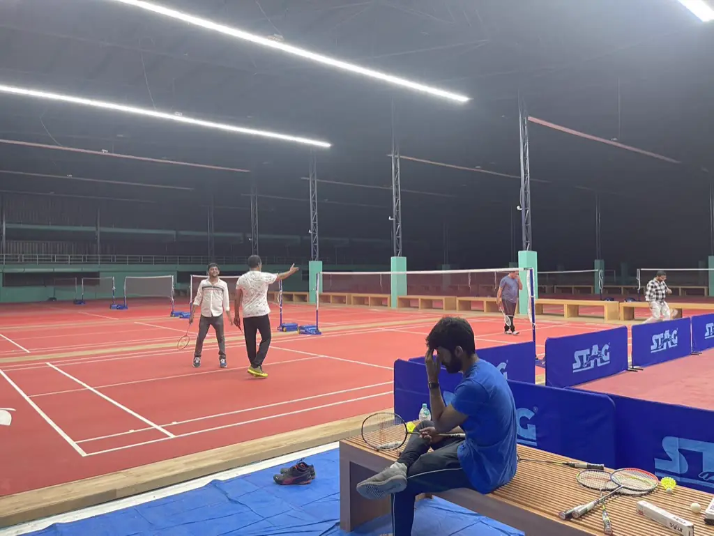 Two friends playing badminton on the red courts