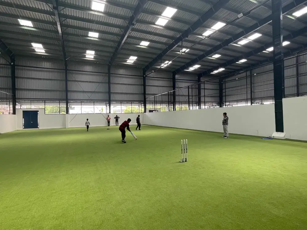 Friends playing cricket on the indoor turf