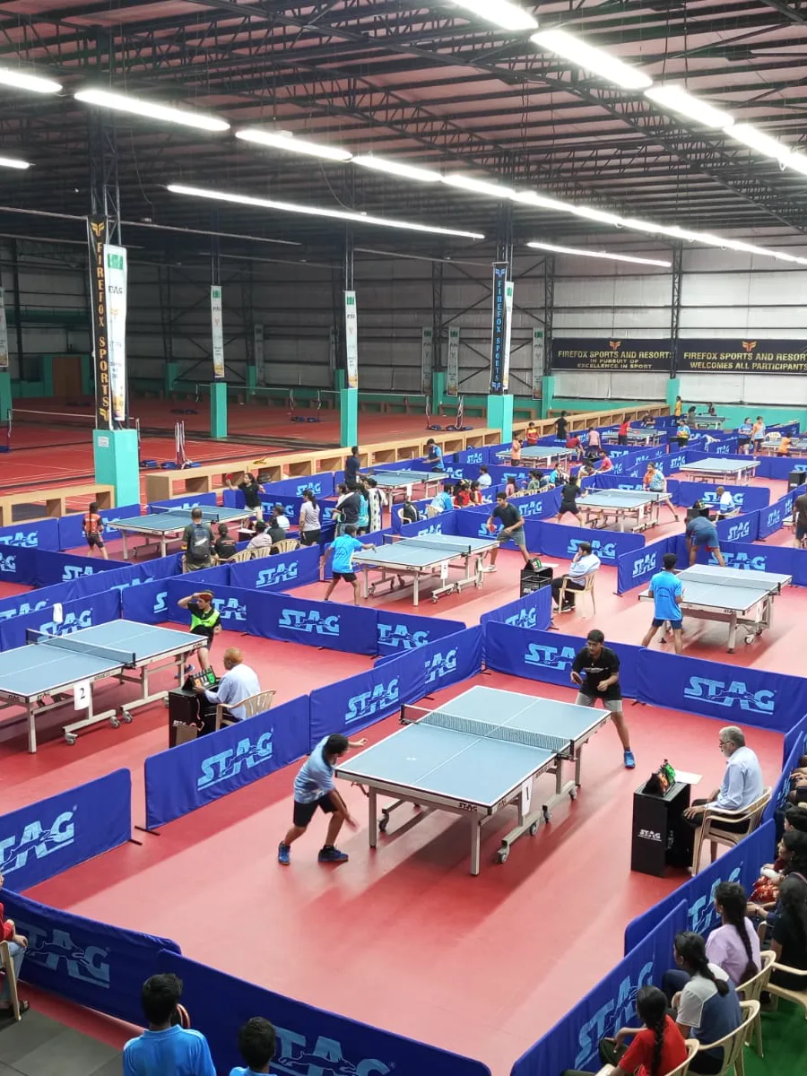 A wide table-tennis hall full of tables