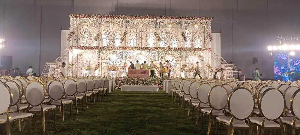 A lawn reception stage with gold chairs at dusk