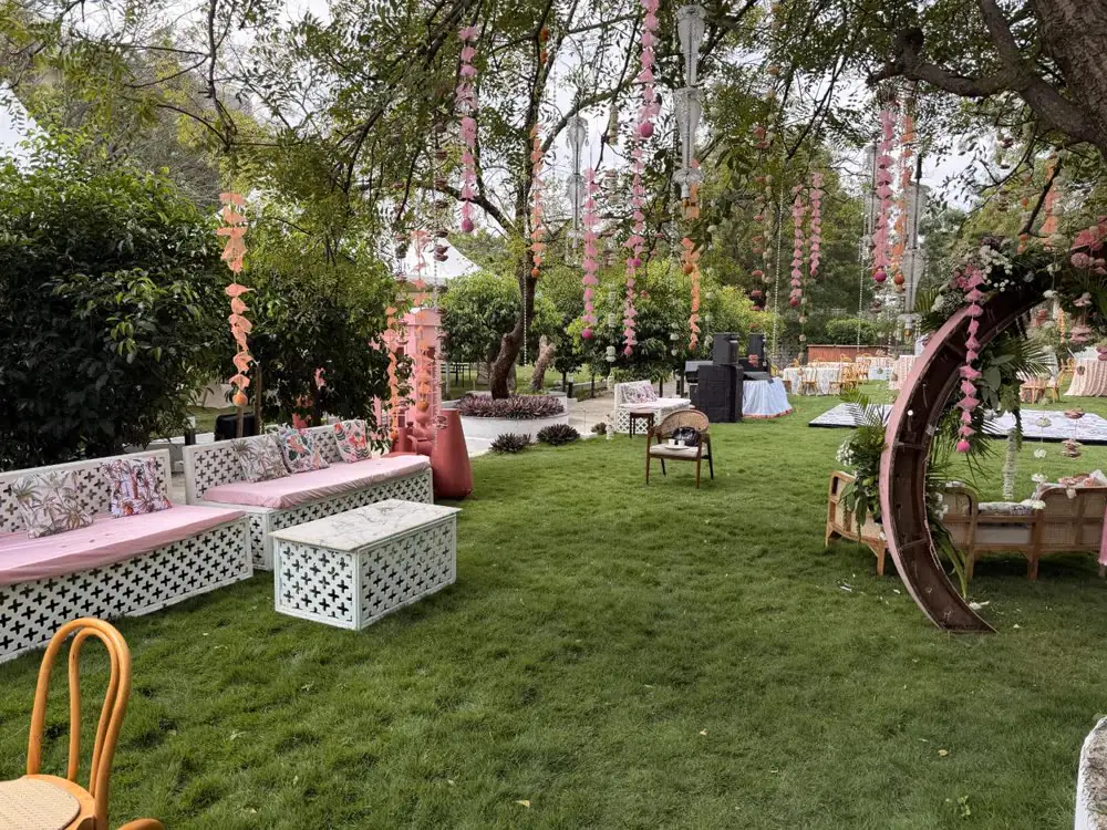 A pastel mehendi lounge on the lawn under hangings in the trees