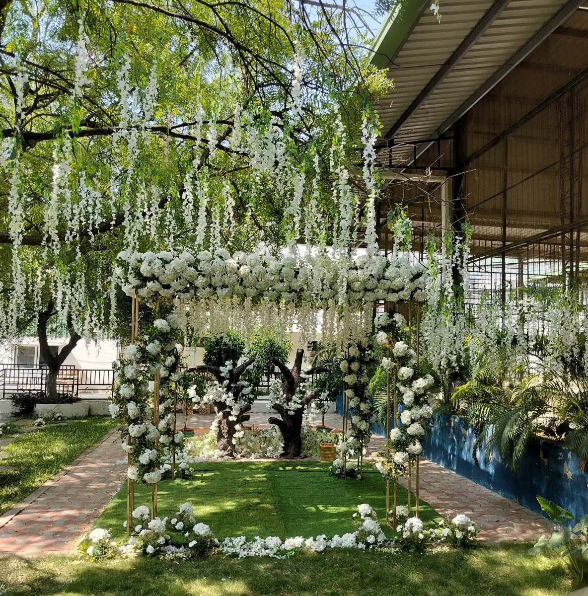 A white floral mandap under hanging blossoms